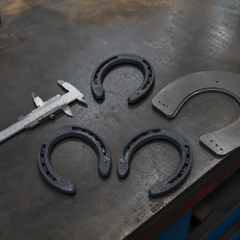 Finished forged steel horseshoes with caliper and profile gauges at an inspection bench