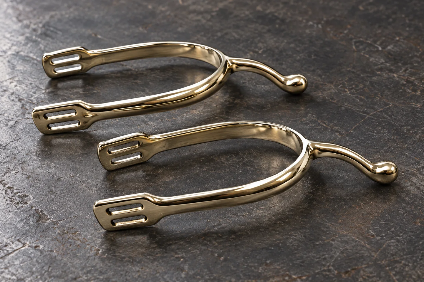 A pair of polished English spurs with swan-shaped necks and rounded ends