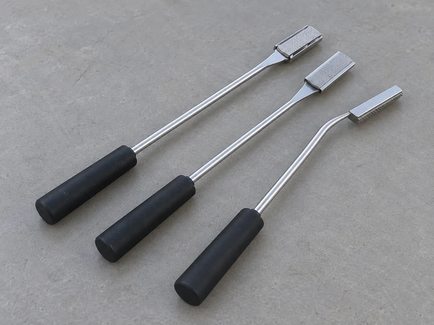Three long equine dental floats with black handles and distinct working-end arrangements