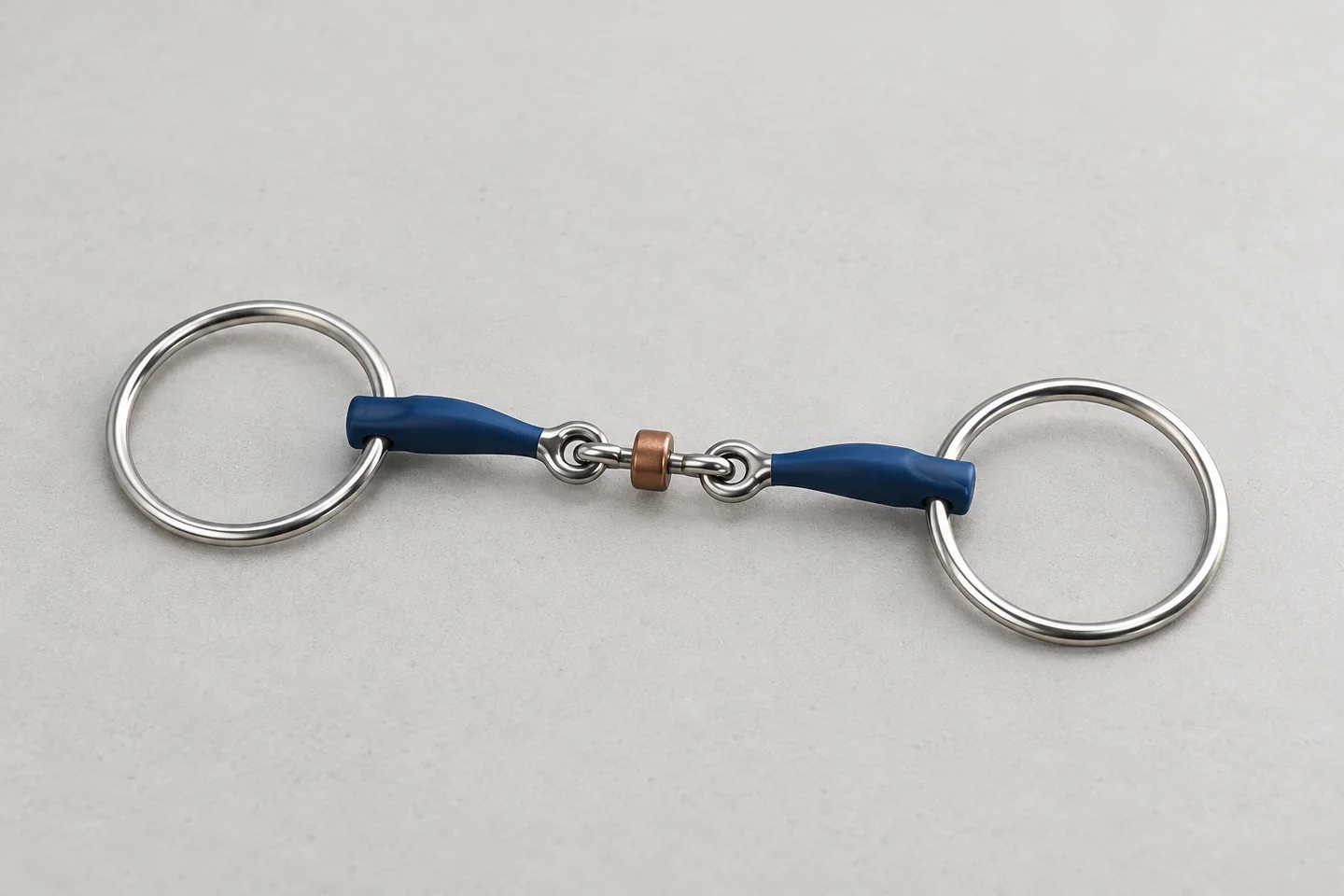 Blue-mouthpiece loose-ring horse bit laid flat on a neutral sample bench