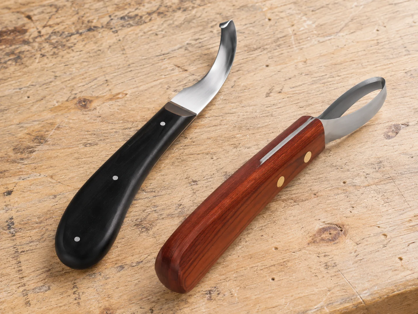 Curved hoof knife and closed-loop hoof knife with different handles on a sample bench
