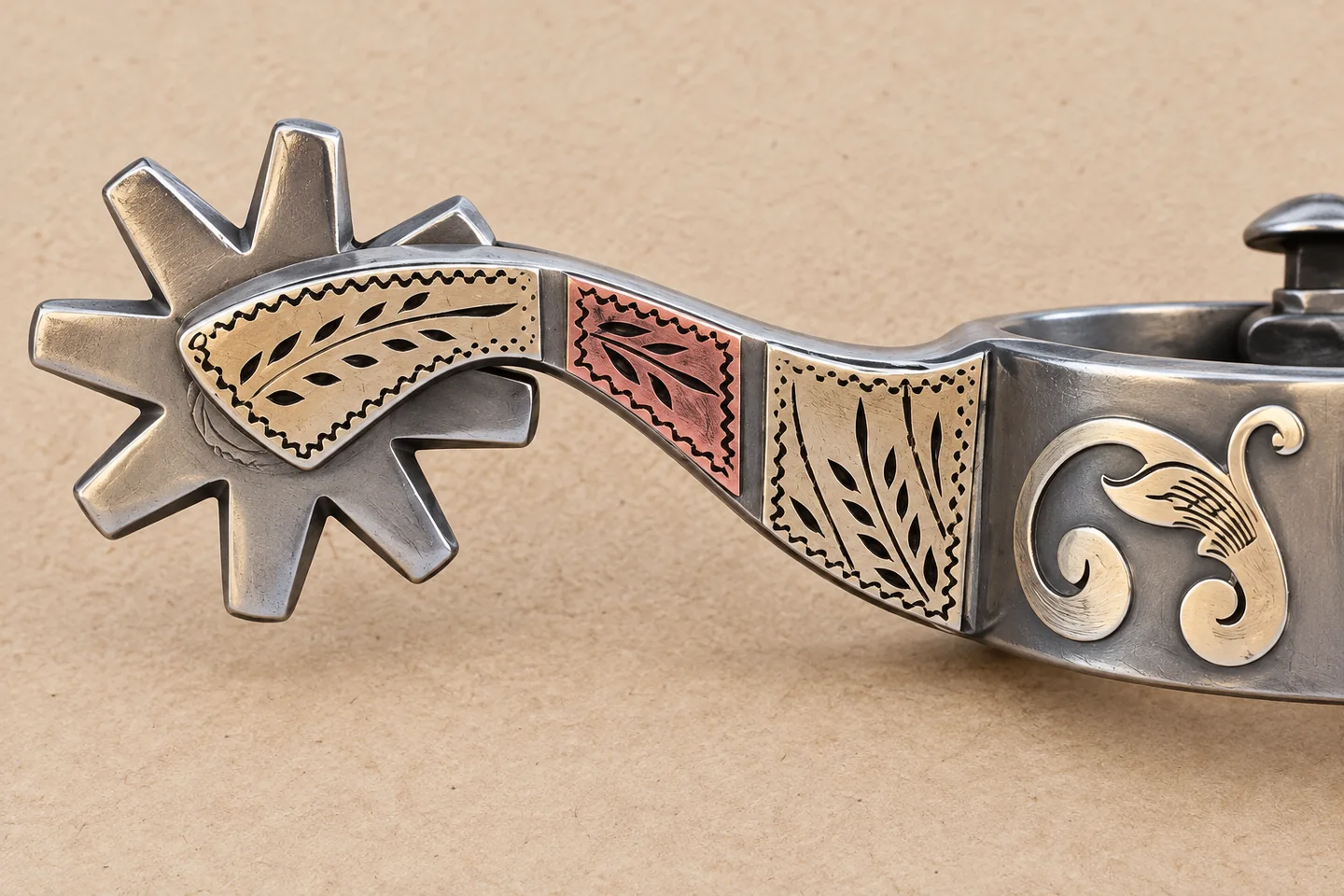 Close view of a star-shaped rowel and decorated shank on a Western spur