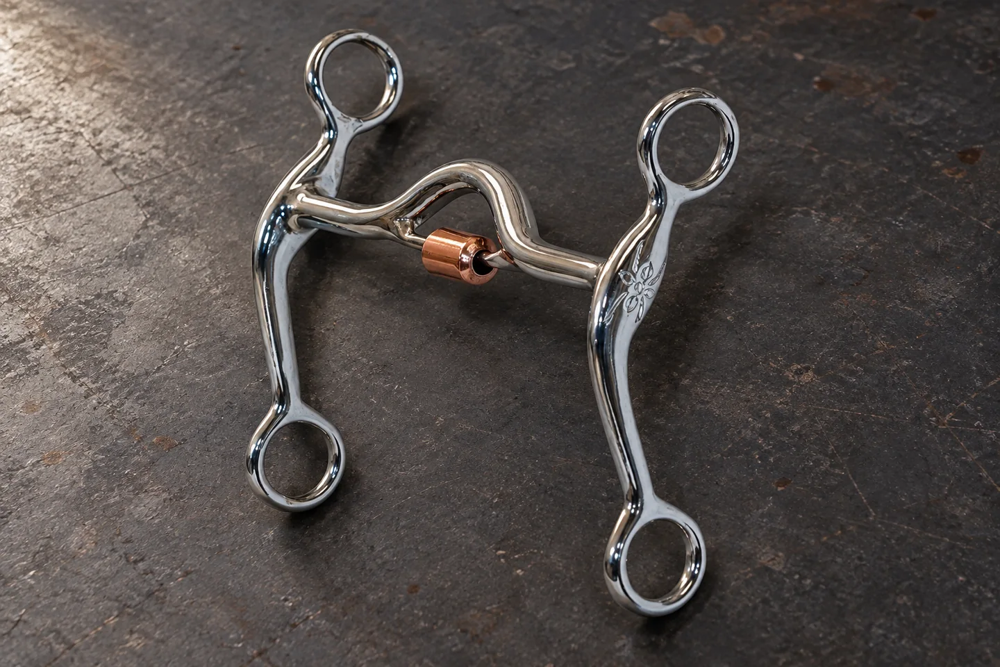A complete curved-shank horse bit with a ported mouthpiece and central roller