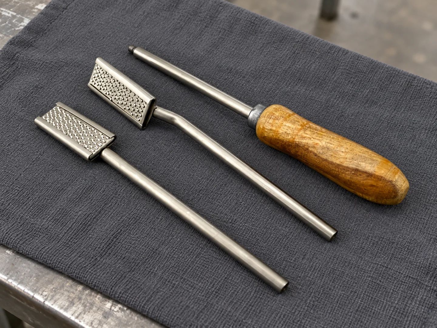 Two separate dental float head-and-shaft pieces beside a wooden-handled shaft