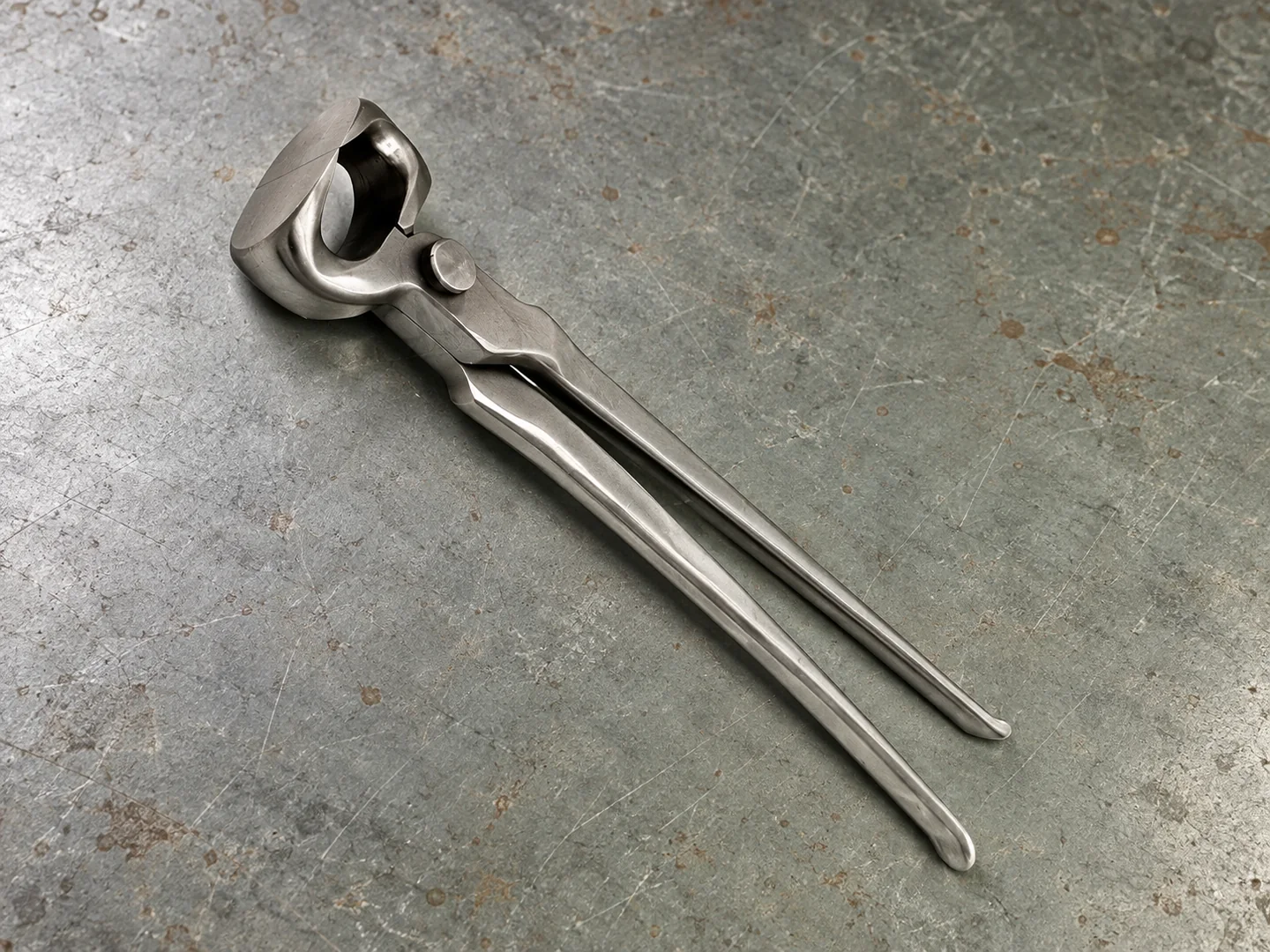 Metal hoof nipper with broad cutting jaws and long handles on a workshop sample bench